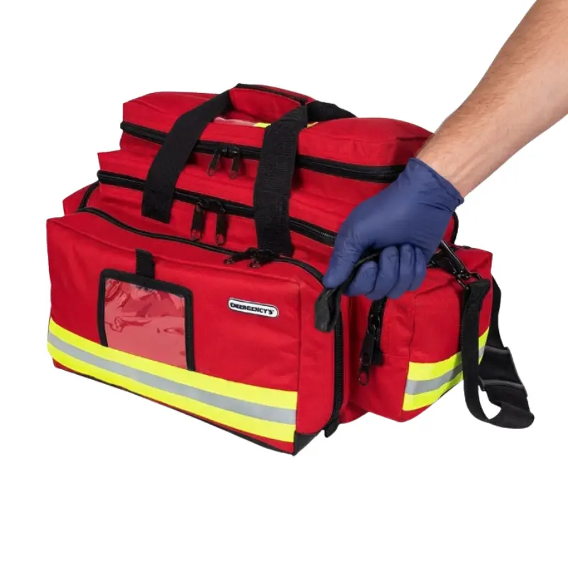 Mano con guante azul sujetando una bolsa de emergencias roja de gran capacidad con bandas reflectantes.