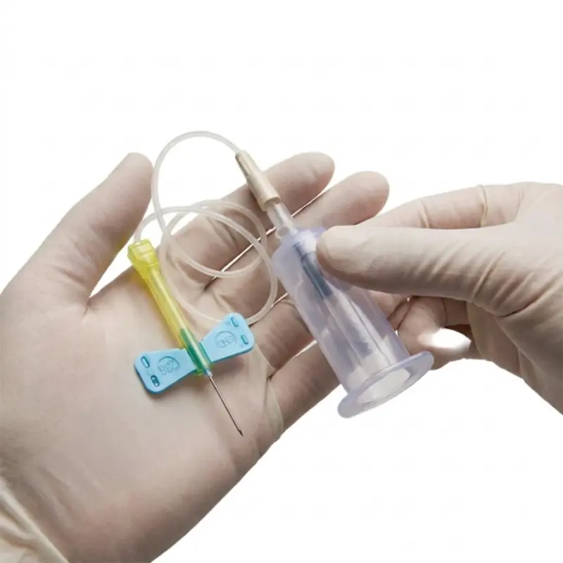 Manos con guantes clínicos sujetando una palomilla de extracción Safety-Lok 23G y su portatubos.