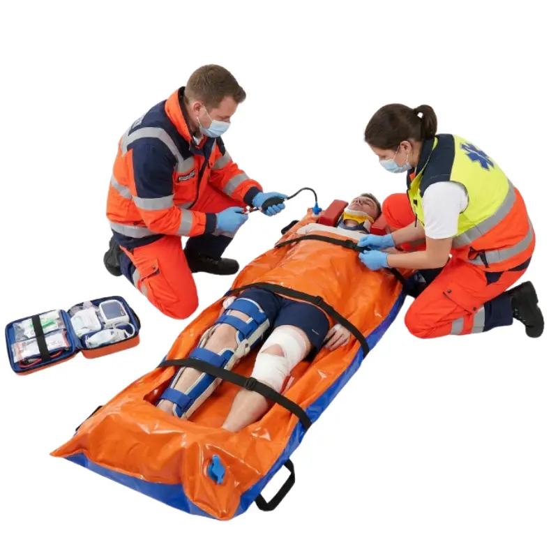 Personal sanitario asistiendo a un paciente inmovilizado sobre un colchón de vacío naranja y azul en una emergencia.