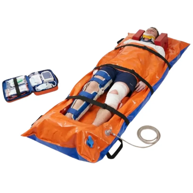 Paciente inmovilizado sobre un colchón de vacío naranja y azul conectado a una manguera de succión en una emergencia.