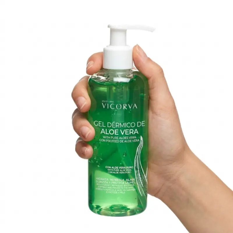 Mano de perfil sosteniendo un envase de gel dérmico de aloe vera VICORVA de 250 ml sobre fondo blanco.