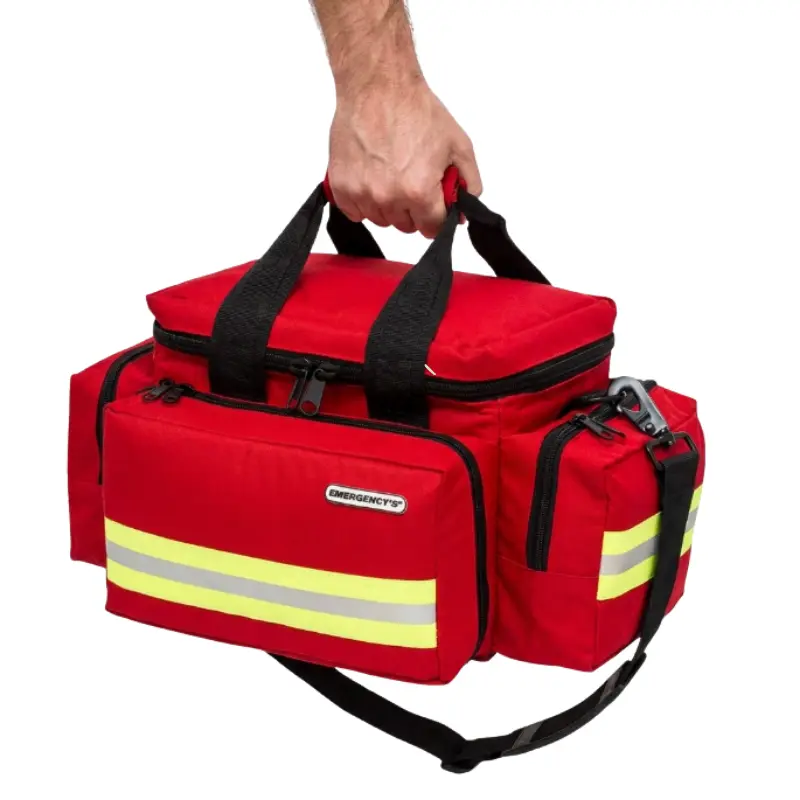 Mano sosteniendo una bolsa ligera de emergencias de color rojo con bandas reflectantes amarillas y asas negras.