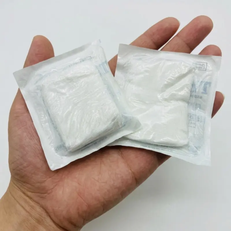Persona sosteniendo en la palma de la mano dos sobres sellados de gasa de algodón estéril en formato clínico.