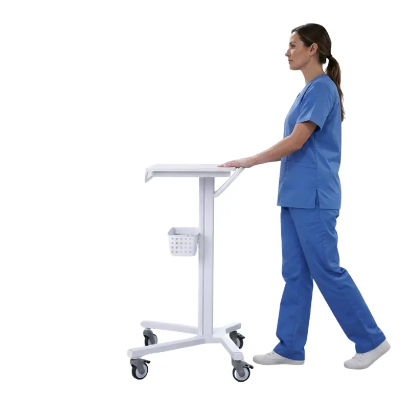 Personal sanitario con pijama azul traslada por el pasillo un carro blanco para monitor de paciente equipado con cesta.