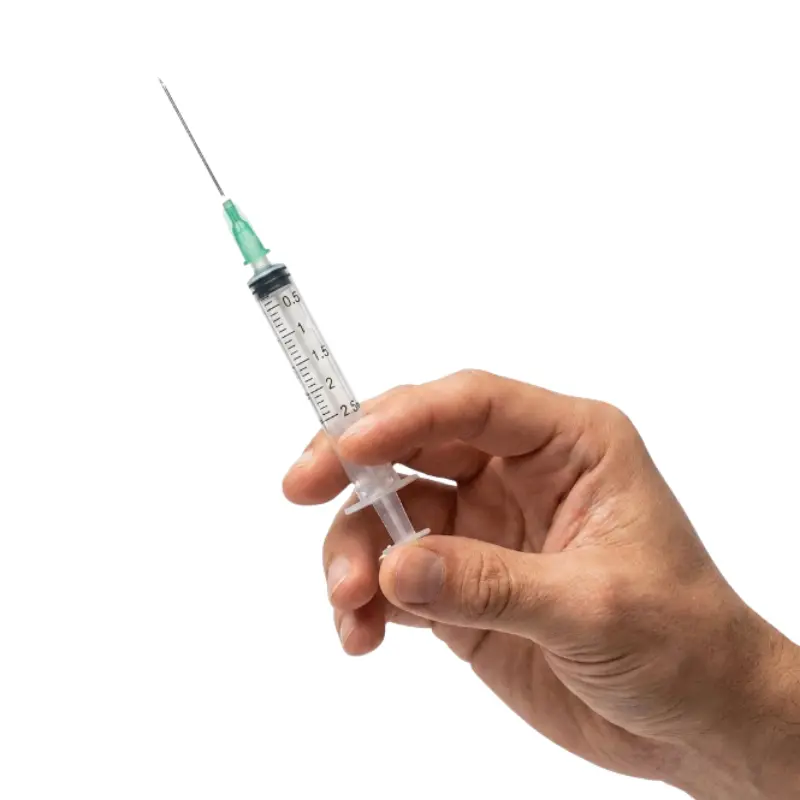 Mano sosteniendo una jeringa transparente de 2,5 ml con aguja fina y cono verde sobre fondo blanco.
