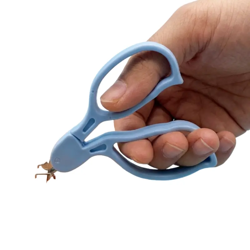 Mano enguantada sujetando un quitagrapa quirúrgico azul preparado para la extracción de suturas en consulta.