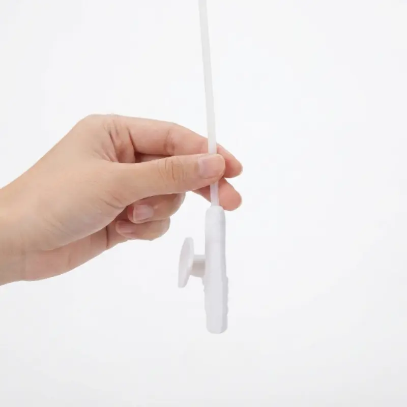 Mano sosteniendo la válvula reguladora y el tubo transparente de una sonda de aspiración CH12 sobre fondo blanco.