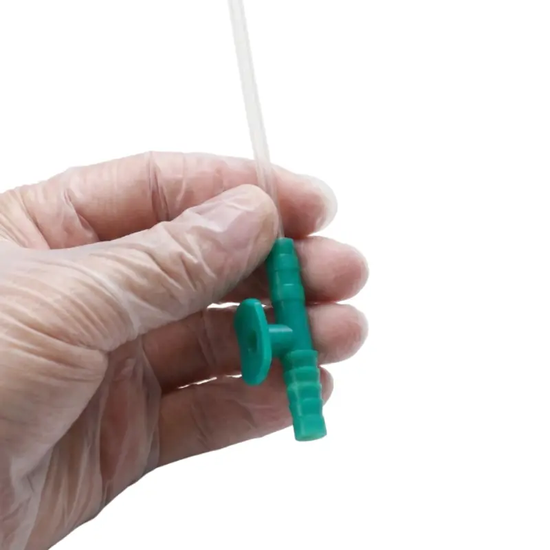 Mano con guante transparente sosteniendo una sonda de aspiración con control CH14 verde para procedimientos.