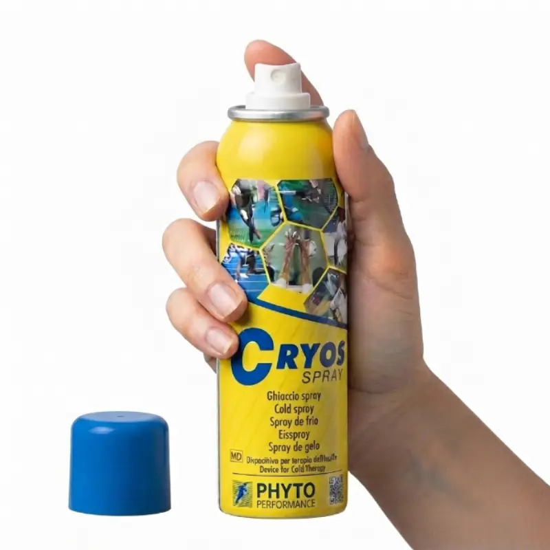 Mano de un usuario presionando el difusor superior de un bote amarillo de spray de frío Cryos Árnica con el tapón azul retirado.