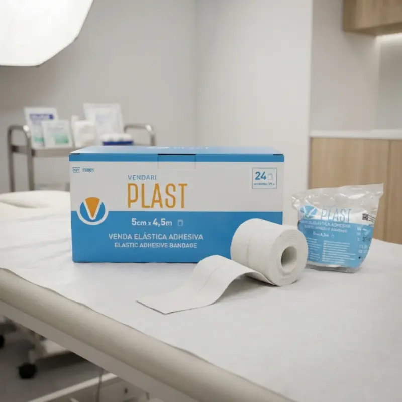 Caja dispensadora azul, rollo y blister de venda elástica adhesiva Vendari PLAST sobre camilla médica.