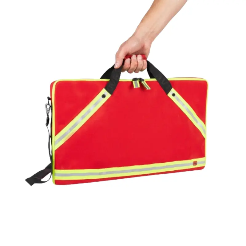 Mano sosteniendo una bolsa porta mangueras BAHO de color rojo con bandas reflectantes amarillas en un entorno clínico.