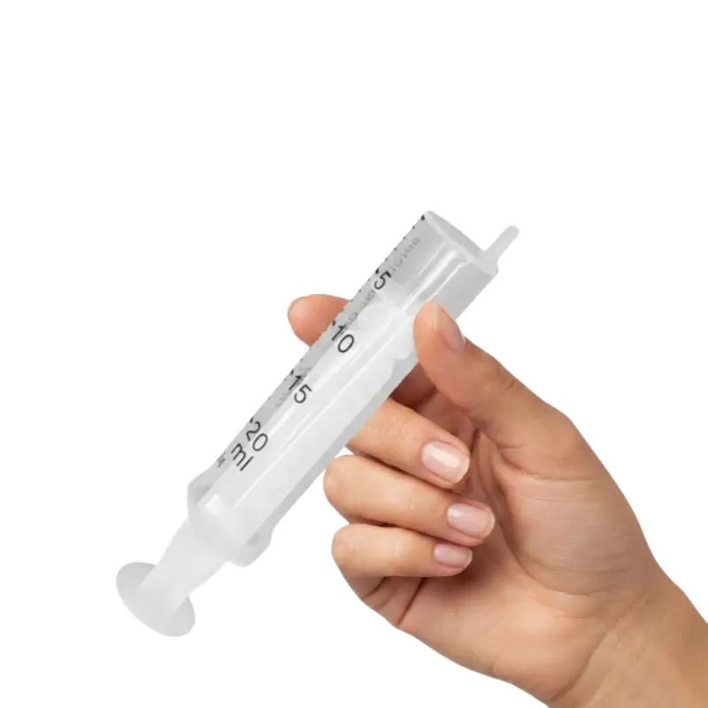 Mano enguantada sosteniendo una jeringa Nipro de 2 cuerpos de 20 ml con escala milimetrada transparente.