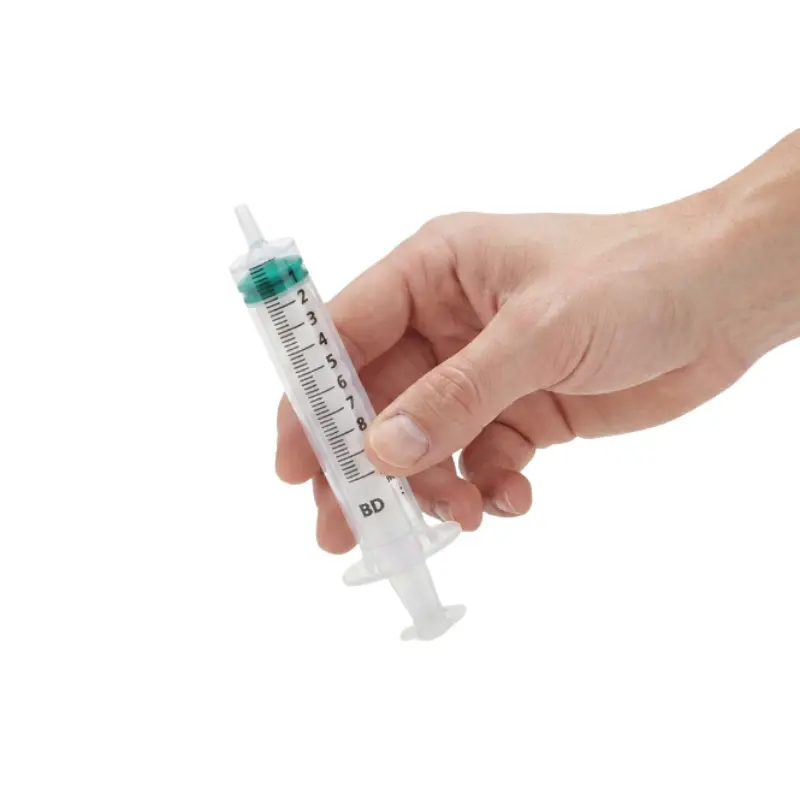 Mano sosteniendo una jeringa transparente de 3 cuerpos BD de 10 ml con escala de graduación detallada.