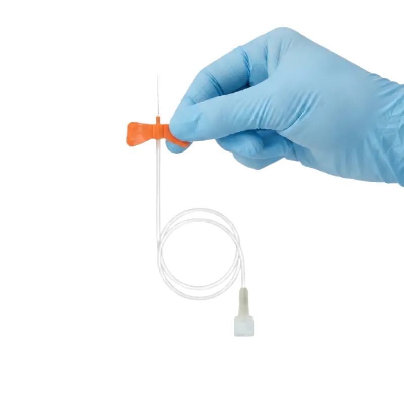 Mano con guante azul sosteniendo por las aletas naranjas una palomilla de infusión Venofix 25G de 19 mm.