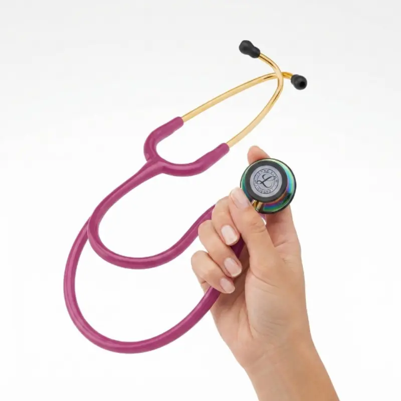 Mano sosteniendo la campana de doble cara de un fonendoscopio Littmann Classic III con tubos frambuesa.