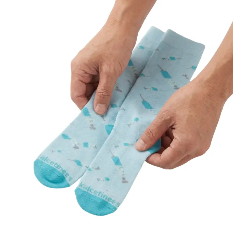 Manos sosteniendo un par de calcetines compresivos azul claro con diseño estampado de jeringas.