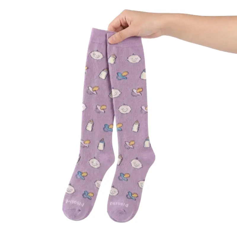 Mano enguantada de un profesional sanitario sosteniendo en alto un par de calcetines compresivos de color lila con estampado pediátrico.