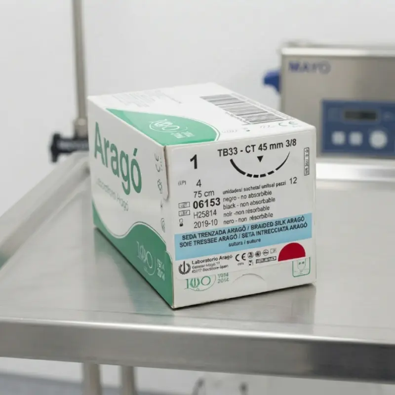 Caja de sutura no absorbible de seda Aragó situada sobre una bandeja de acero inoxidable en un entorno clínico.