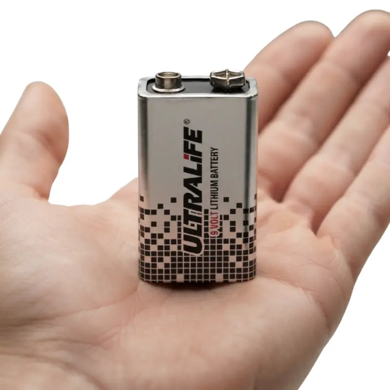 Batería de litio Ultralife de 9V sostenida en la palma de una mano para mostrar su tamaño escala real.