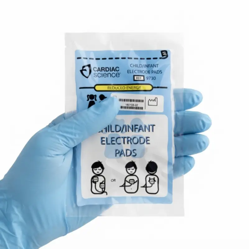 Mano con guante azul sosteniendo el envase de los electrodos pediátricos Cardiac Science Powerheart G3.