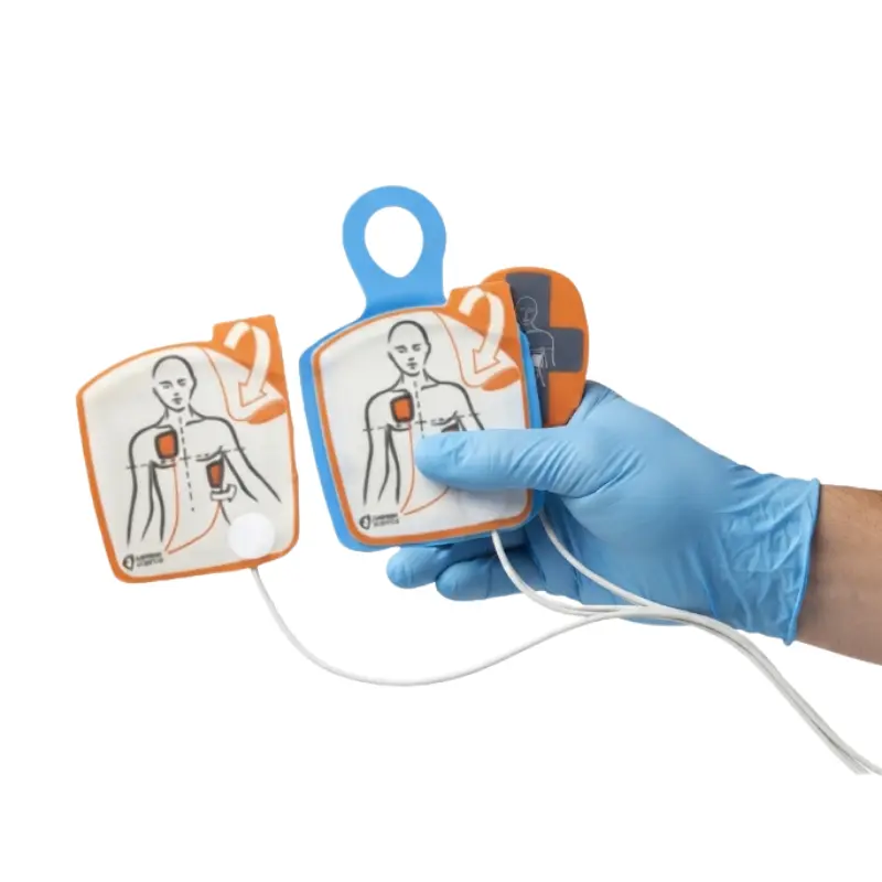 Mano con guante azul sosteniendo los electrodos de adulto con sensor CPRD para el desfibrilador Powerheart G5.