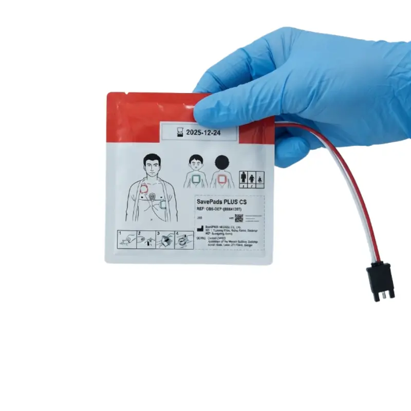 Mano con guante azul sosteniendo el sobre sellado de los electrodos Primedic HeartSave myPAD con cable y conector.