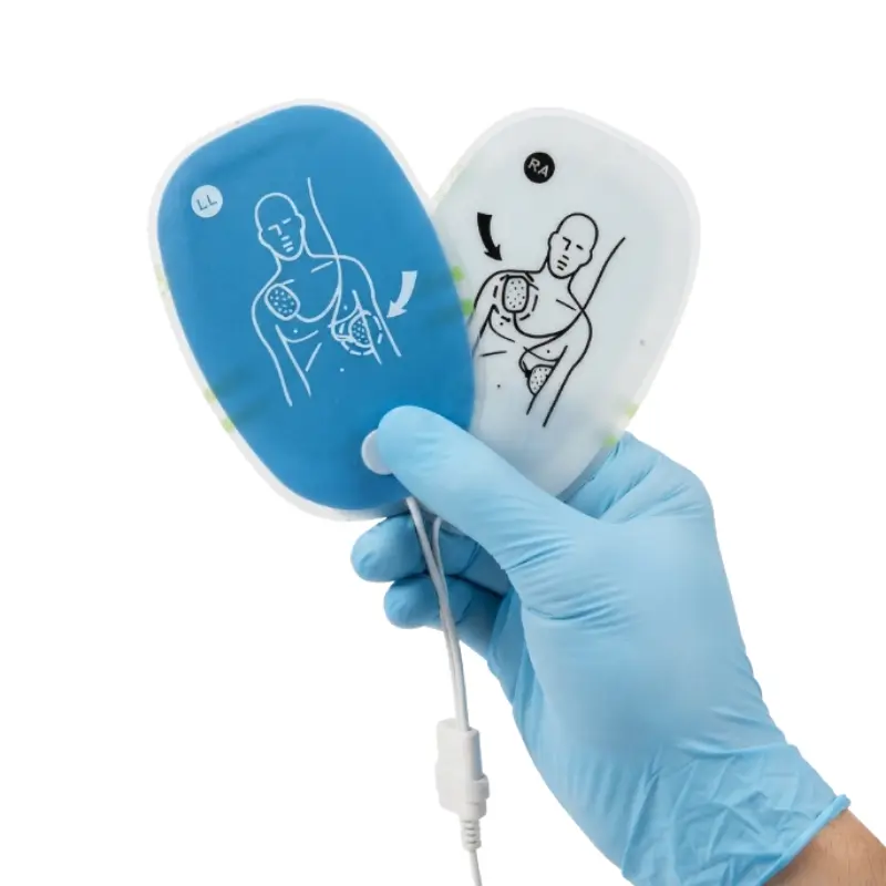 Mano con guante azul sujetando dos parches de electrodos de adulto para el desfibrilador AMOUL i3.