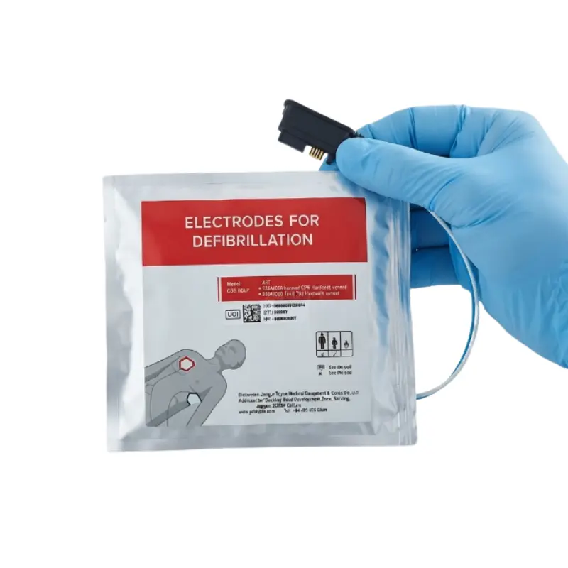 Mano con guante azul sujeta el conector de los electrodos adulto/pediátrico Primedic HeartSave en su bolsa.