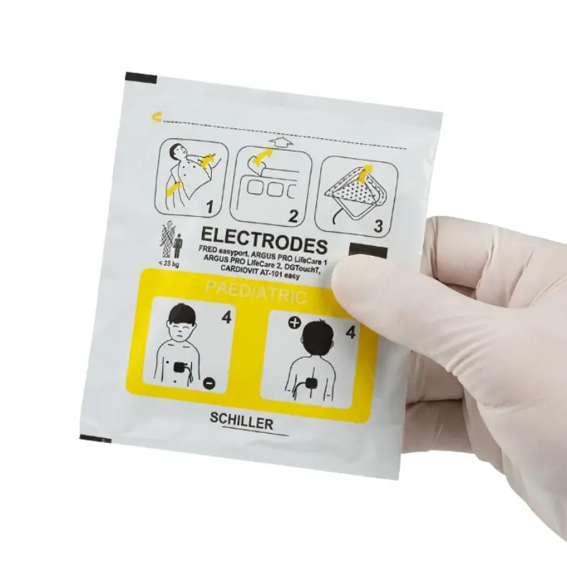 Persona con guante blanco sostiene el envase sellado de los electrodos pediátricos Schiller Fred Easyport.