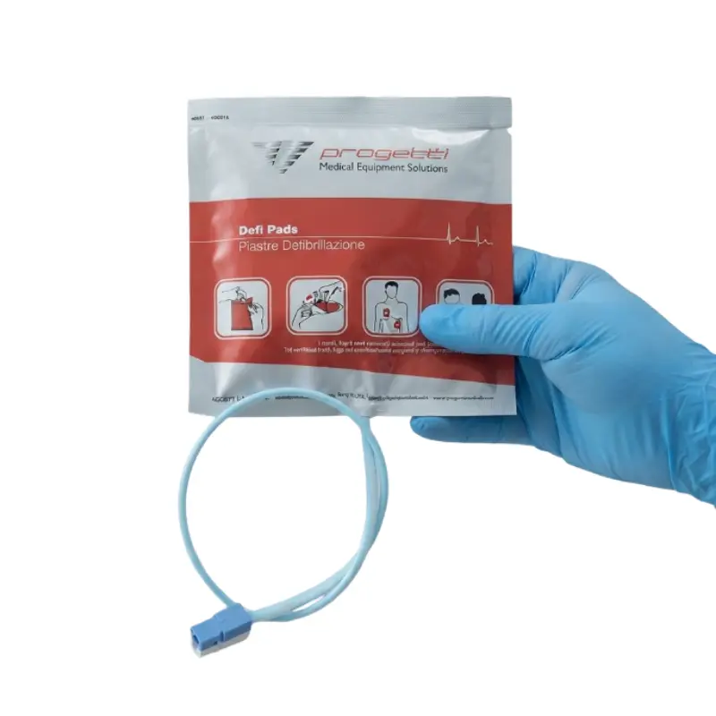 Mano con guante azul de nitrilo sosteniendo el envase estéril de los electrodos preconectados Rescue Sam Progetti.
