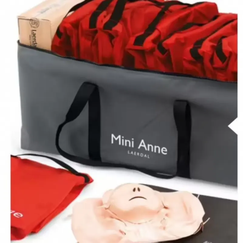 Bolsa de transporte gris abierta con múltiples estuches rojos y un maniquí Mini Anne Plus desplegado en primer plano.