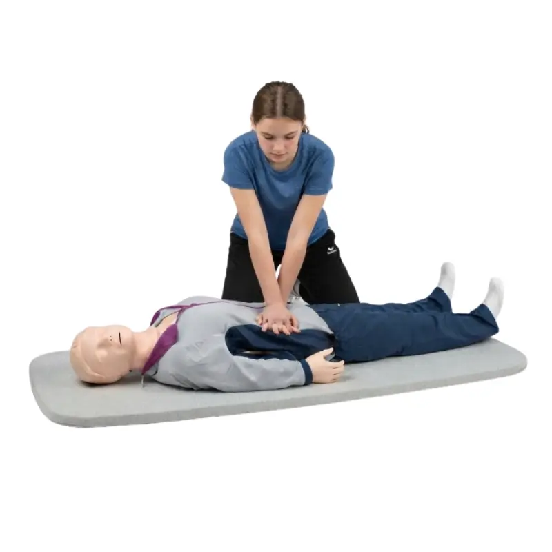 Persona practicando compresiones torácicas sobre el maniquí de RCP de cuerpo entero Laerdal Resusci Anne QCPR.
