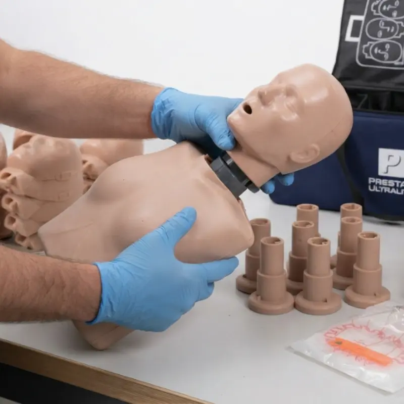 Persona con guantes azules ensamblando la cabeza de un maniquí de RCP Prestan Ultralite sobre el torso.