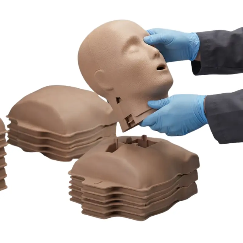 Sanitario con guantes azules ensamblando la cabeza de un maniquí de RCP Prestan Ultralite de tono oscuro.