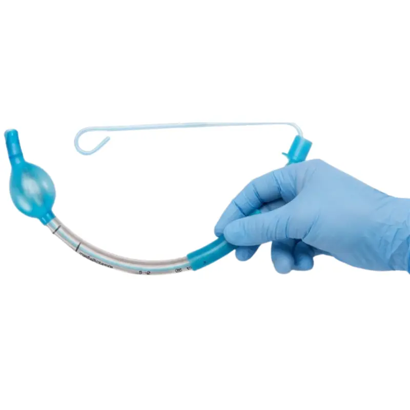 Mano con guante azul de nitrilo sujetando un tubo endotraqueal transparente con guía estéril y balón azul.