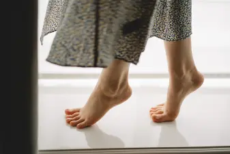Mujer levantada sobre las puntas de los pies en un salón luminoso para activar la circulación muscular y prevenir piernas cansadas.