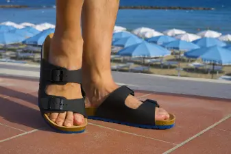 Persona caminando por un paseo marítimo usando sandalias durante un día soleado de verano.