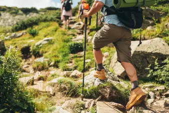 Persona caminando por un sendero al aire libre con zapatillas de montaña, ideal para evitar las piernas cansadas.