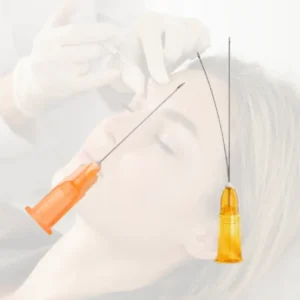 Composición visual que contrasta una microcánula de estética de punta roma y una aguja hipodérmica sobre un rostro difuminado.
