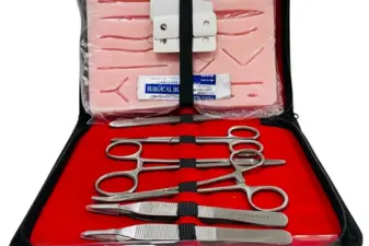 Estuche negro abierto que contiene un kit de sutura con instrumental quirúrgico de acero y una almohadilla sintética.