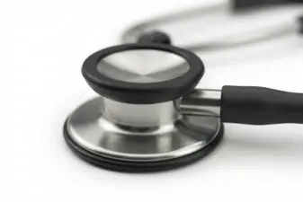Primer plano de la campana metálica y el diafragma de un fonendoscopio sobre fondo blanco brillante.