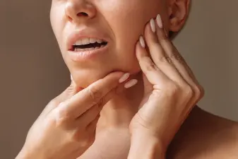 Detalle de una mujer tocando su línea mandibular para tratamientos de remodelación y armonización facial.