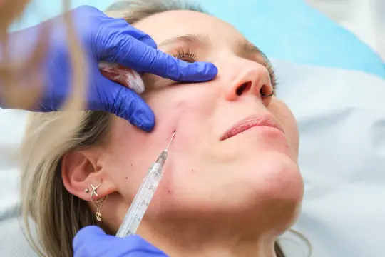 Aplicación de tratamiento facial con cánula en una clínica de medicina estética.