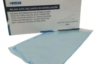 Caja de bolsas auto-sellantes de esterilización Klmed junto a una bolsa azul desplegada sobre una superficie blanca.